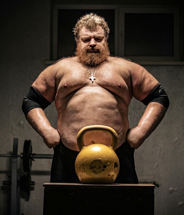 Man performing a powerful strength exercise in a dark gym.